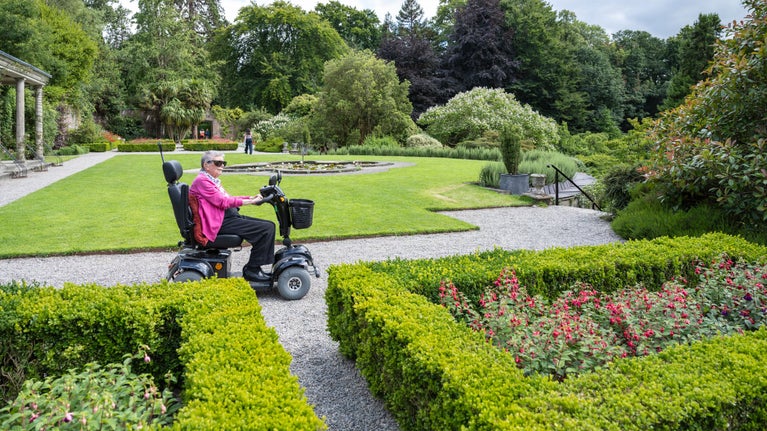A visitor using a motorised scooter enjoys the Walled Garden at Penrhyn Castle